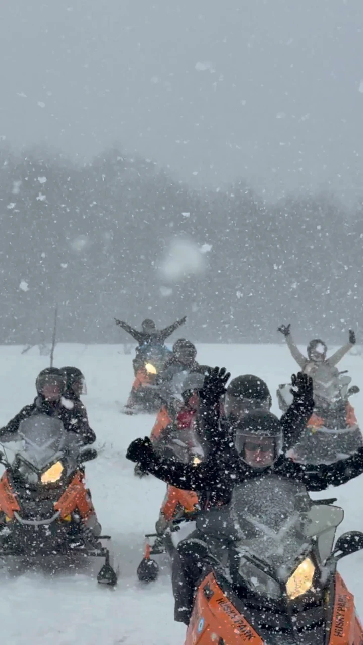 Snowmobile group in falling snow